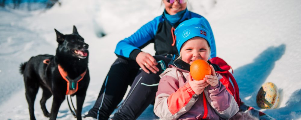 En barn som holder en appelsin på skitur